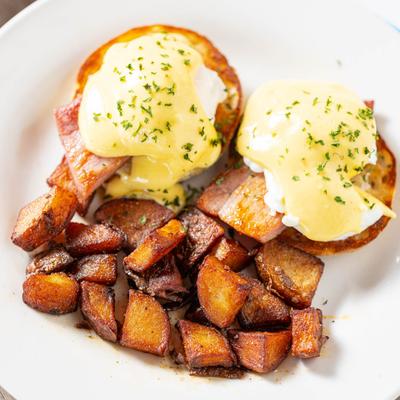 Eggs Benedict with a side of roasted potatoes.