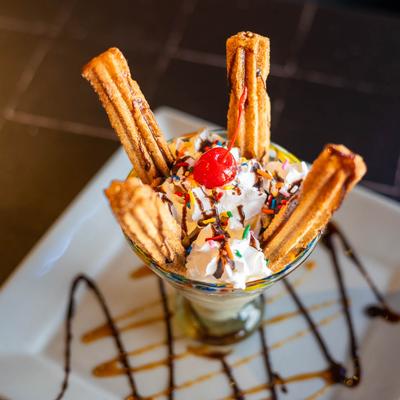 Churros served with whipped cream, sprinckles and a cherry.