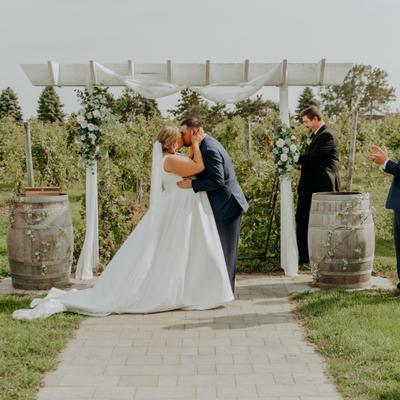 Wedding couple kissing under the arch in the vineyard at Next Chapter Winery.
