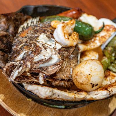 Grilled steak, fish, shrimp, sausage, peppers, and onions.