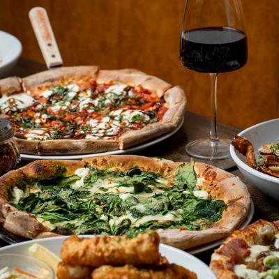 Florentine pizza and Caprese pizza served with a glass of red wine.