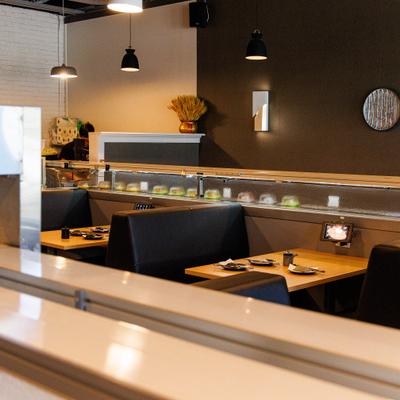 Interior of a sushi restaurant featuring modern pendant lighting and dark leather booths.