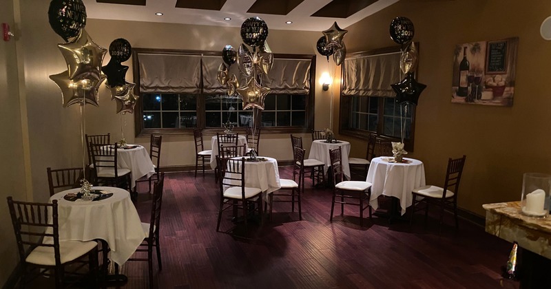 Inside, tables set for a celebration, featuring black and gold balloons