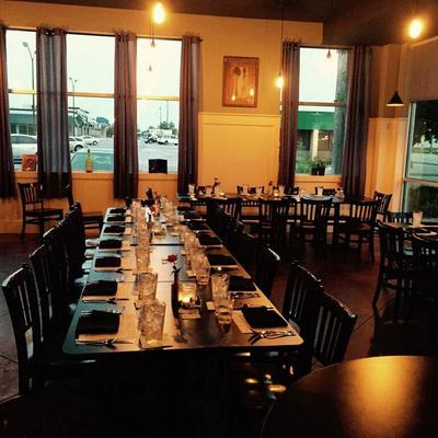 Dining room with a long table set for service and large windows.