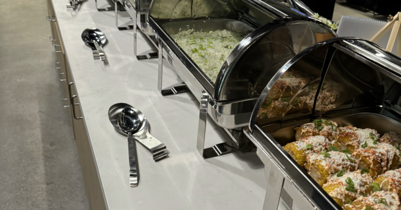 Lined up chafing dishes with assorted food on a table