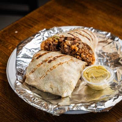 Stuffed burrito served with a small cup of salsa.