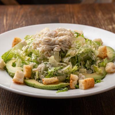 Crab salad served over greens with avocado slices and croutons.