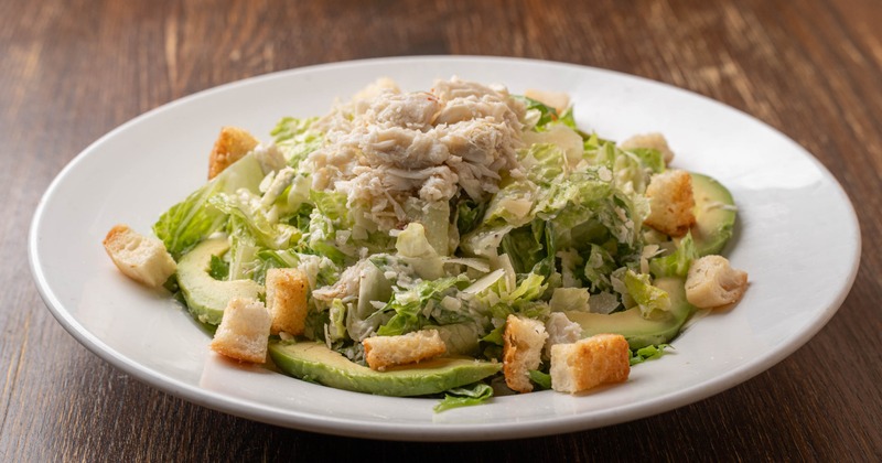 Crab salad on the bed of greens served with avocado slices and croutons