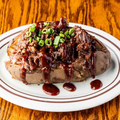 Baked potato loaded with smoked brisket, scallions, and BBQ sauce.