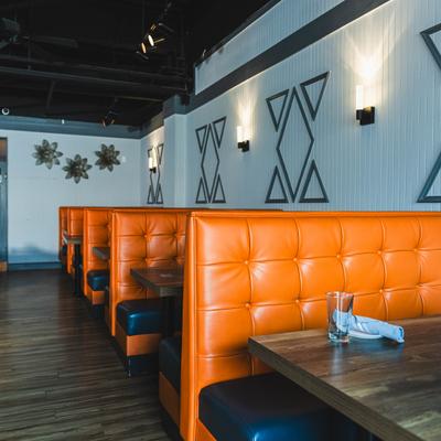 Dining room featuring orange leather booths and geometric wall decorations.