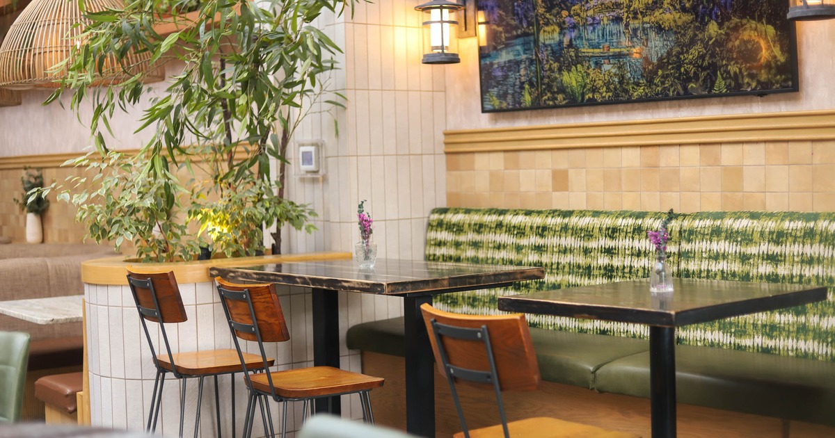 Interior, banquette bench with wooden top tables and chairs, plant decoration