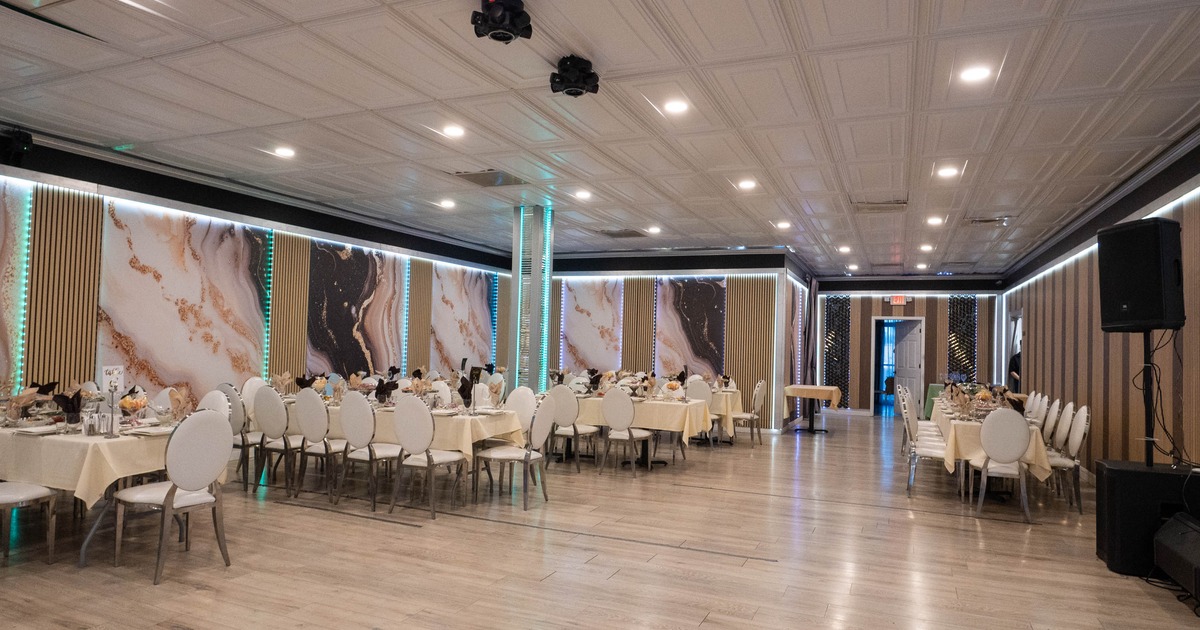 Spacious banquet hall - elegant decor, tables set for an event and marble-patterned wall art.