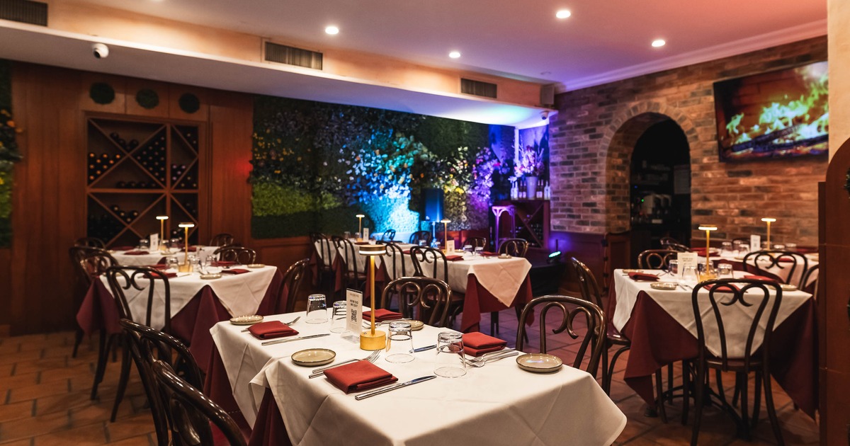 Elegant restaurant interior with dim lighting, white tablecloths, and wooden chairs