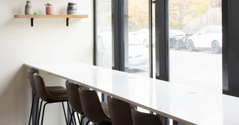 Modern interior with a white countertop, brown chairs, near large windows