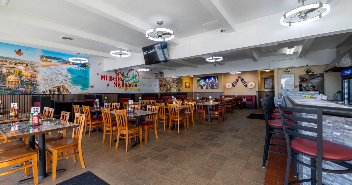 Interior - wooden tables, chairs, mural-covered walls, modern light fixtures; a counter, high chairs