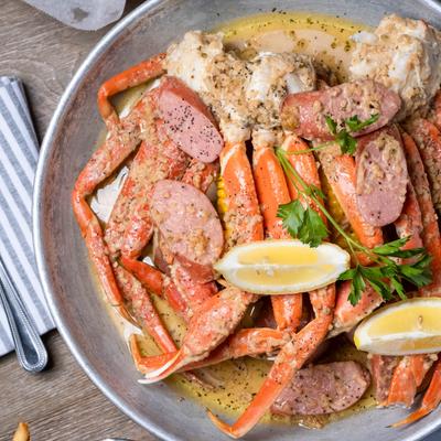 Crab set with crab legs, lemon, and sausage, top down view.
