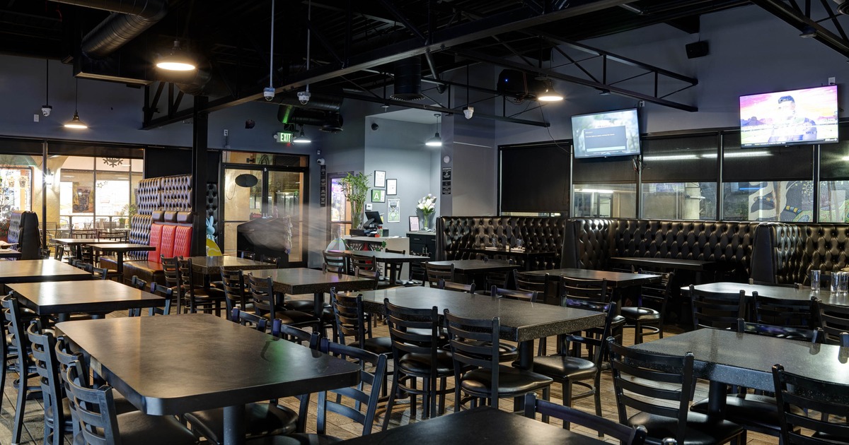 Interior with tables, chairs, booths, mounted TVs and ceiling lights