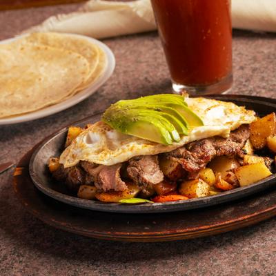 Breakfast Skillet served with tortillas on the side and a glass of Bloody Mary.