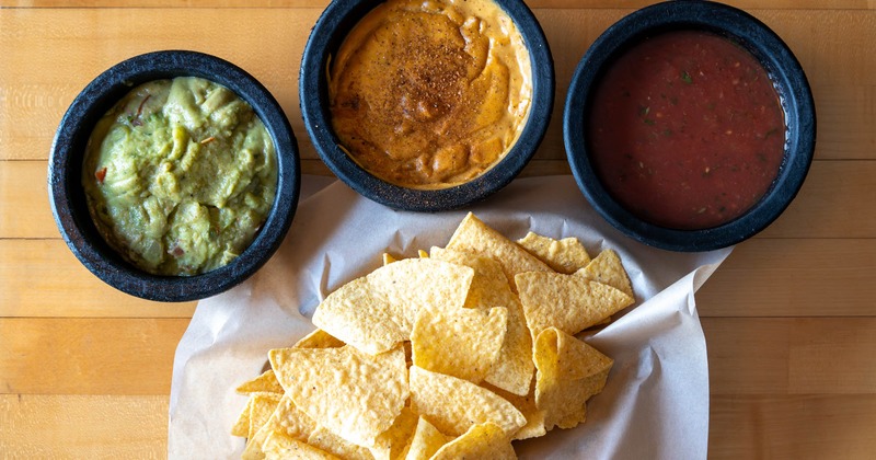 Tortilla chips with guacamole, red salsa, and cheese dip