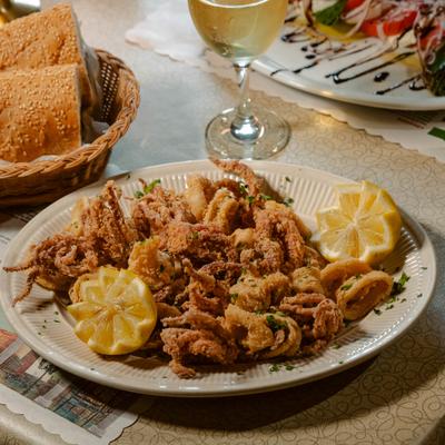 A plate of crispy fried calamari served with fresh lemon wedges.