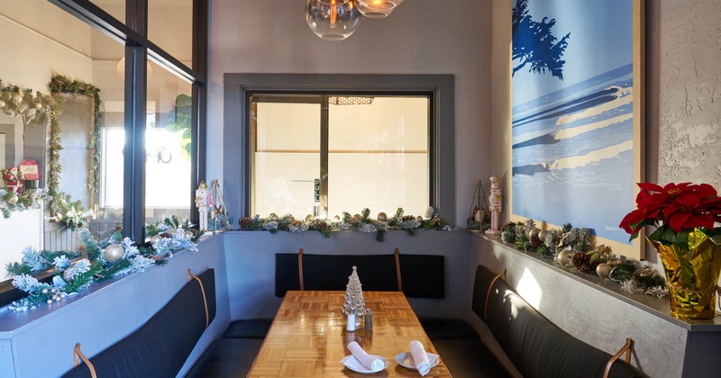 Dining alcove with holiday decorations, featuring a wooden table, cushioned benches