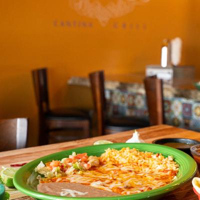 A plate of enchiladas served with refried beans and rice.