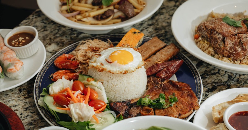 Table spread with multiple dishes with Vietnamese broken rice dish in the center