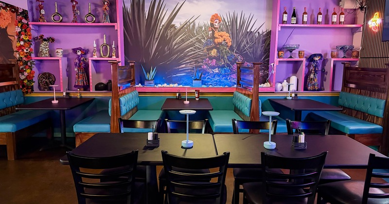 Interior - turquoise-cushioned booths, dark wooden tables, a Day of the Dead mural