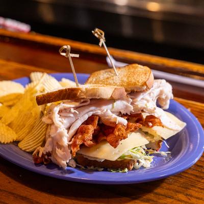 Turkey Club sandwich served on a blue plate with a side of chips.