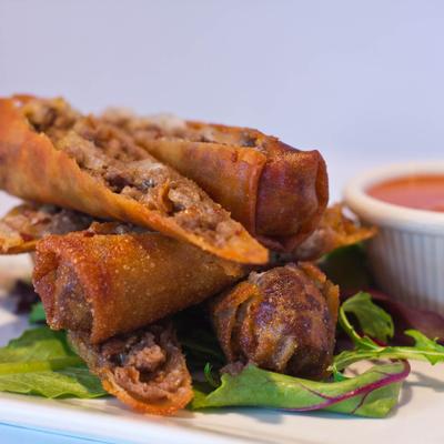 Spring rolls with a red sauce for dipping.