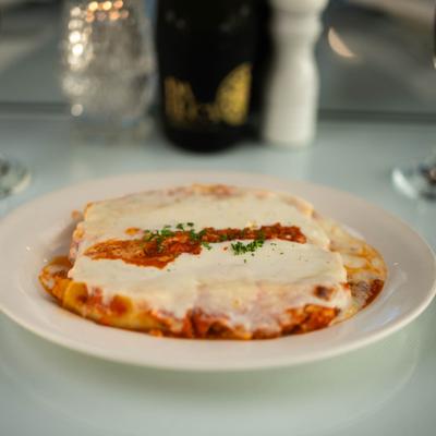 A serving of Lasagna alla Bolognese on a white table.