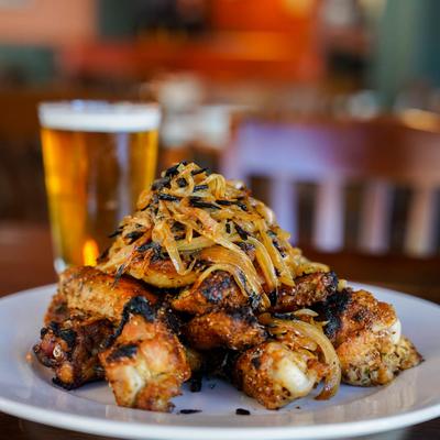 Coal fire chicken wing plate on a table with beer.