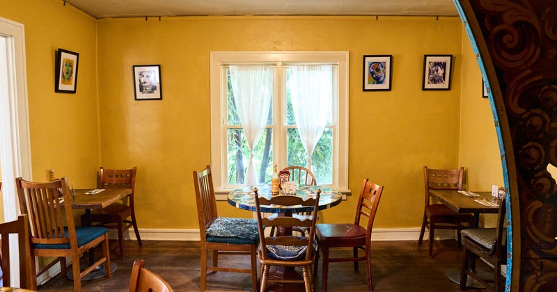 Interior, tables by a window, small framed pictures on yellow walls