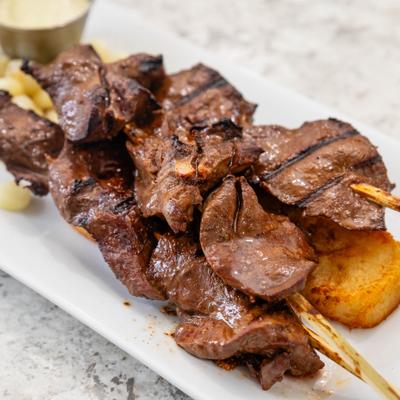 Grilled beef heart skewers served over potatoes.