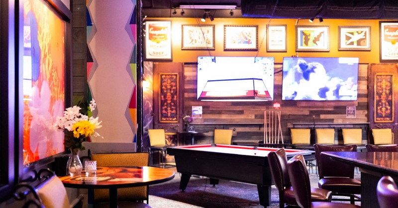 A cozy bar setting featuring a pool table and  TVs on the wall