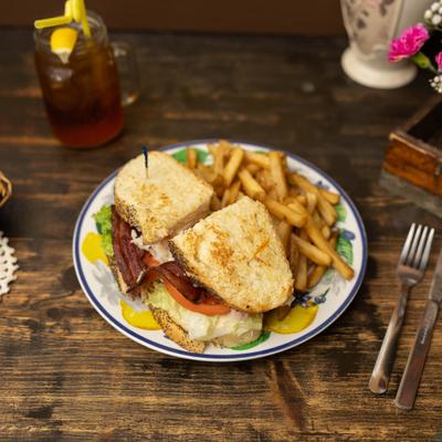 Ham, turkey, and BLT club sandwiches served with fries.