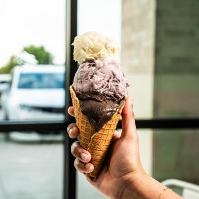 A hand holding an ice cream cone.