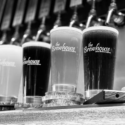 Brewhouse pints full of beer sitting under taps.
