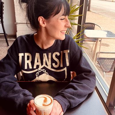 A smiling person holding a drink.