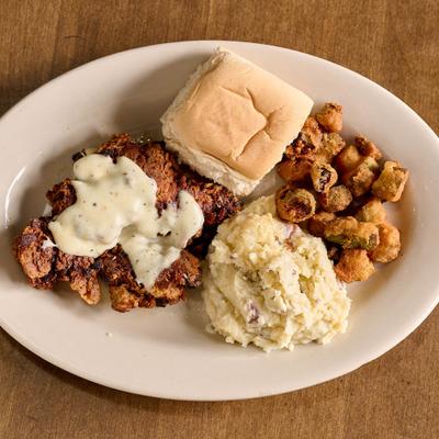 Fried chicken livers topped with gravy, served with mashed potatoes, fried okra and a bread roll.