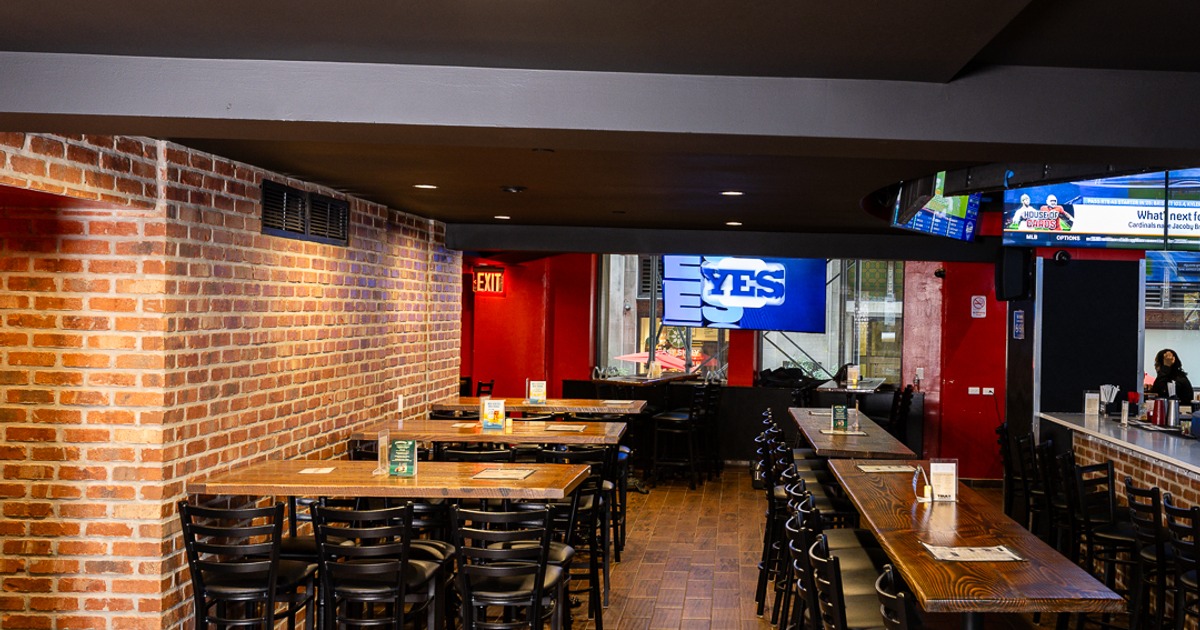 Long dining area with tables, chairs, brick walls and bar seating