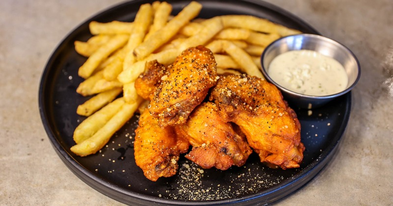 Chicken wings sprinkled with pepper, served with golden fries and ranch