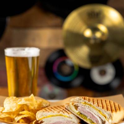 Sliced ham and sliced pork panini served with chips  and beer.