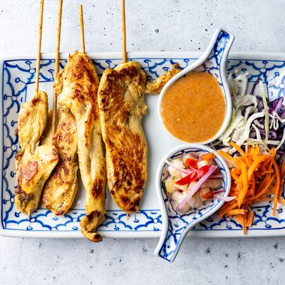 Thai chicken satay with peanut sauce and salad on a plate.