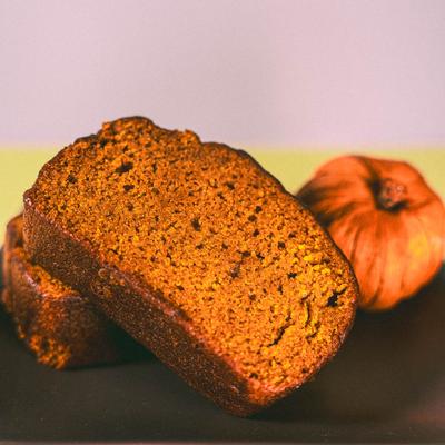 Pumpkin bread loaf slices with a whole pumpkin in the background.