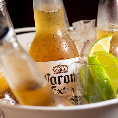 Ice bucket with bottles of Mexican lager and glass with lime wegdes.