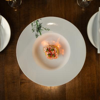 Flaming sushi appetizer presented on a large white plate.