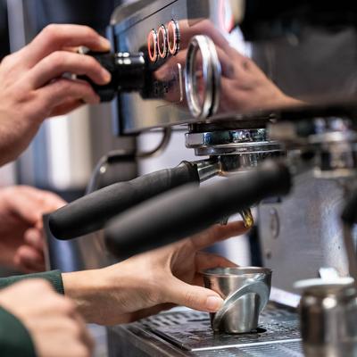 Hands operating the espresso machine.
