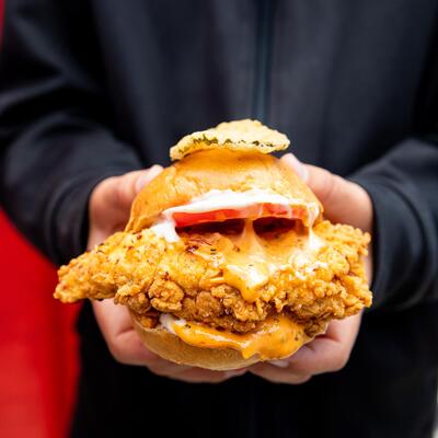 Hands holding a fried chicken slider.