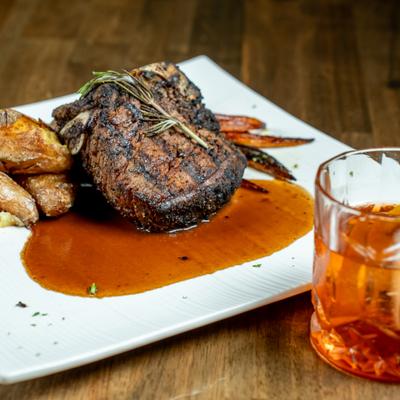 Bone in filet mignon roasted carrots and potatoes and bourbon on the rocks.